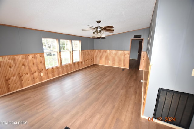 empty room with ornamental molding, a textured ceiling, ceiling fan, light hardwood / wood-style flooring, and lofted ceiling