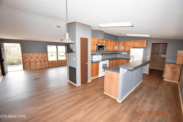 kitchen featuring lofted ceiling, white appliances, a kitchen island with sink, hardwood / wood-style flooring, and a textured ceiling