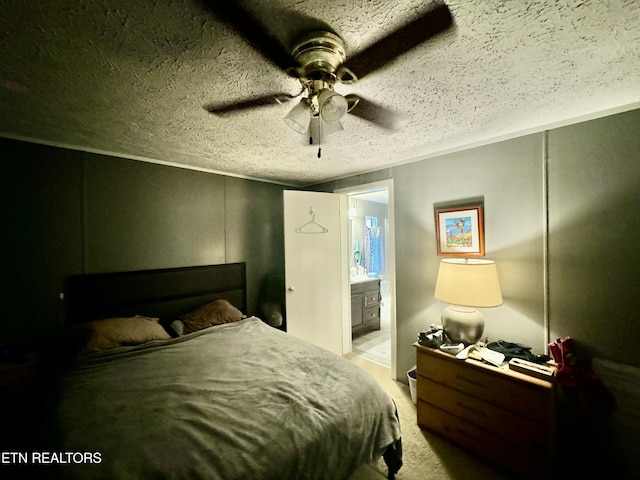 bedroom with a textured ceiling, light colored carpet, ensuite bath, and ceiling fan