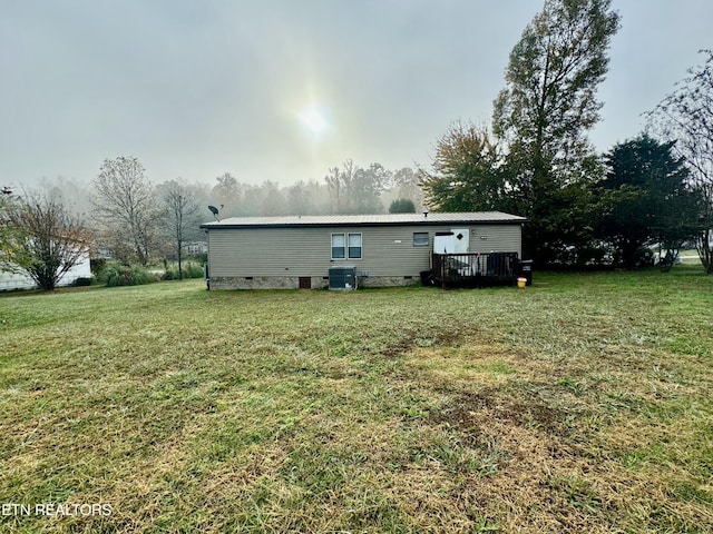 rear view of property featuring a lawn, a wooden deck, and central AC unit