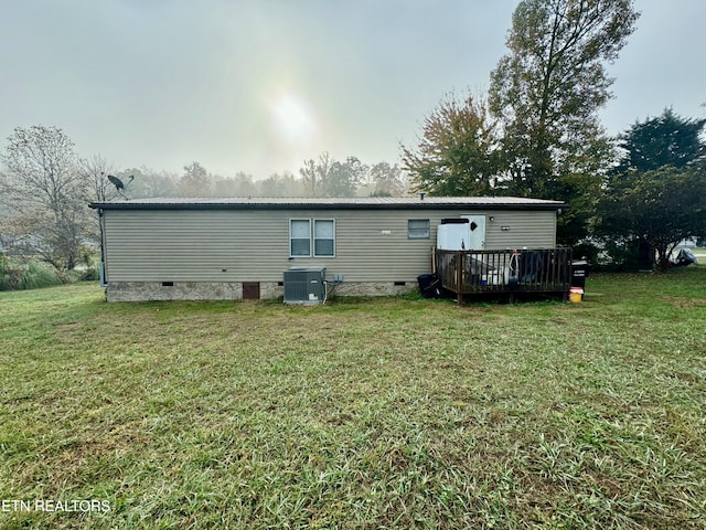 rear view of property with central air condition unit, a lawn, and a deck