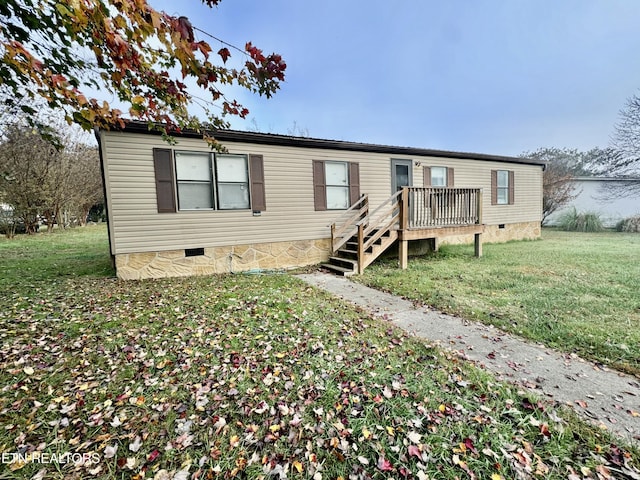 manufactured / mobile home with a front yard and a wooden deck