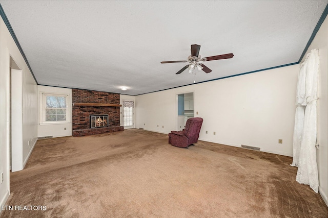 unfurnished living room with carpet, ceiling fan, a textured ceiling, and a brick fireplace