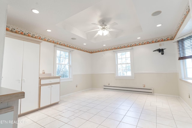 tiled empty room featuring ceiling fan, a baseboard heating unit, and a tray ceiling