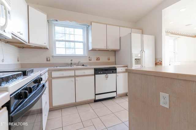 kitchen with white cabinets, light tile patterned floors, white appliances, and sink