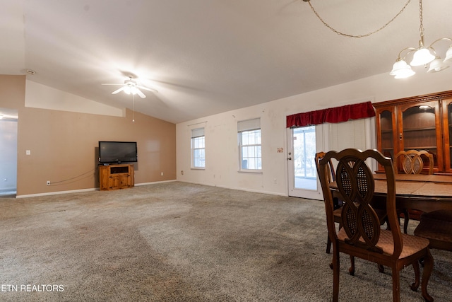 carpeted dining area featuring ceiling fan with notable chandelier and lofted ceiling