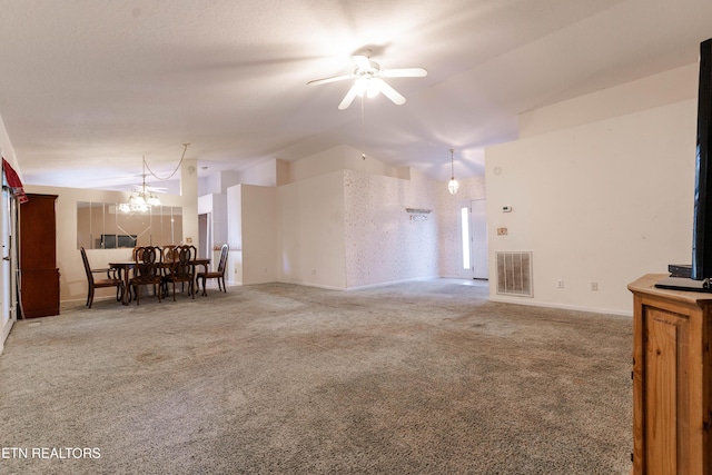 carpeted living room featuring vaulted ceiling and ceiling fan with notable chandelier