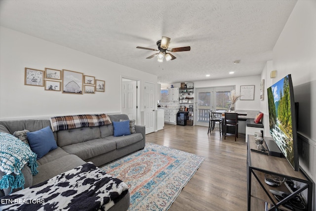 living room featuring ceiling fan, wood-type flooring, and a textured ceiling