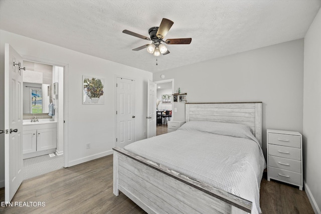 bedroom with sink, dark hardwood / wood-style floors, ceiling fan, a textured ceiling, and connected bathroom