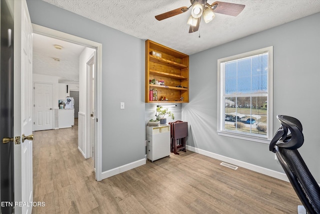 office featuring light wood-type flooring, a textured ceiling, and ceiling fan