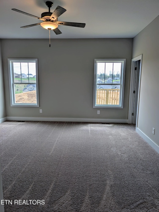 carpeted spare room featuring baseboards, ceiling fan, and plenty of natural light