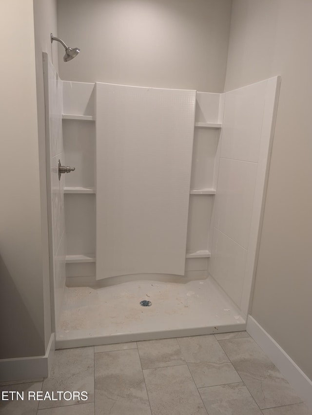 bathroom featuring a stall shower and baseboards