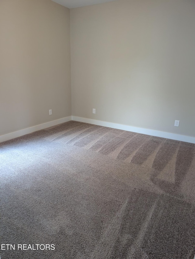carpeted spare room featuring baseboards
