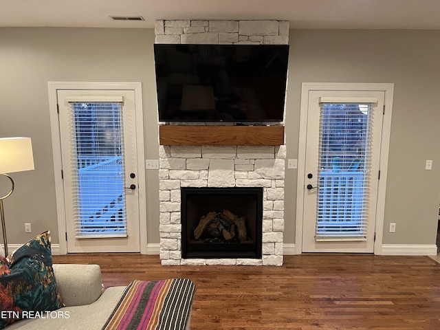 living room with wood-type flooring and a stone fireplace