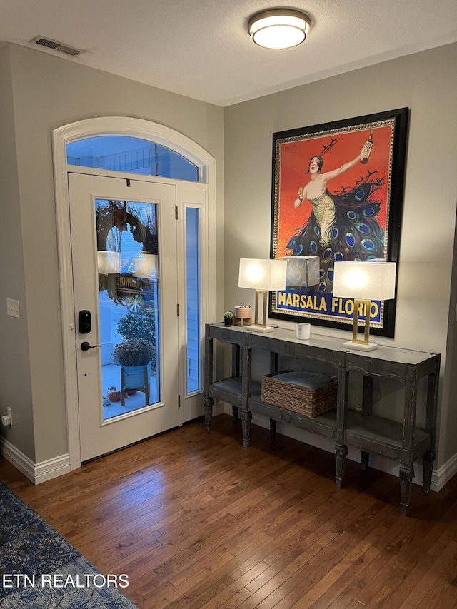 foyer entrance featuring a textured ceiling and dark hardwood / wood-style floors