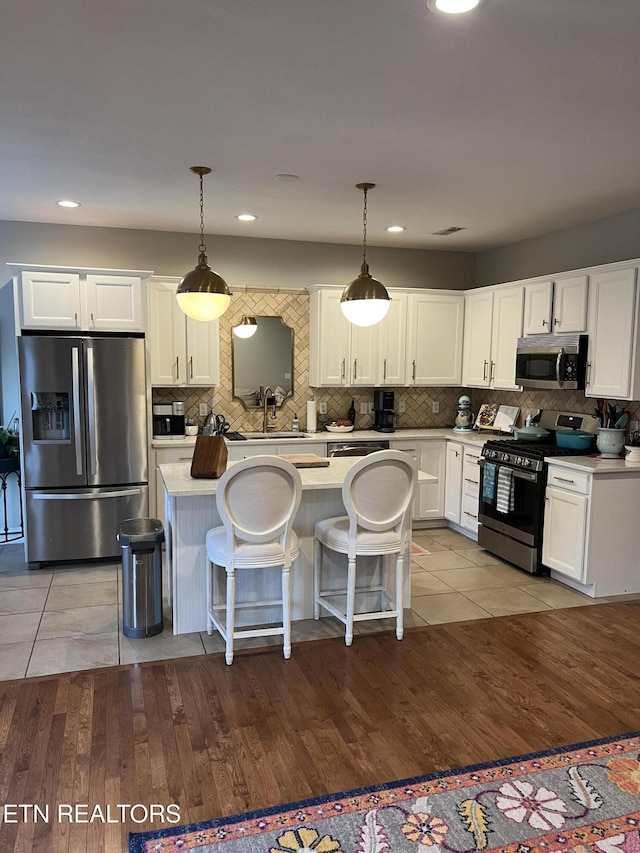 kitchen with appliances with stainless steel finishes, light hardwood / wood-style floors, and decorative light fixtures