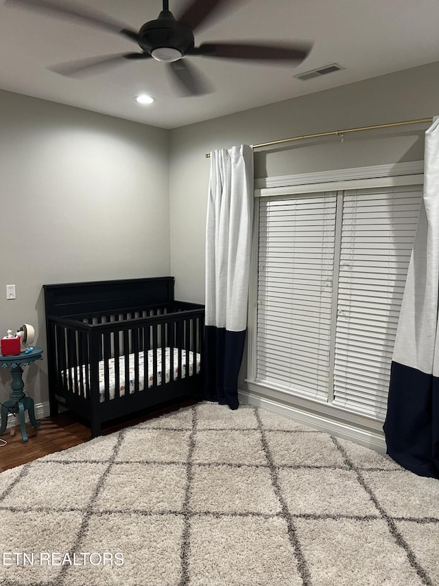 bedroom with ceiling fan, hardwood / wood-style floors, and a nursery area