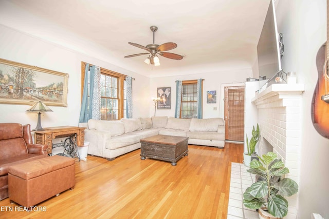 living room with ceiling fan, wood-type flooring, and a brick fireplace