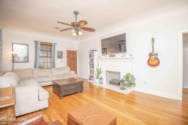 living room featuring hardwood / wood-style flooring, a brick fireplace, and ceiling fan