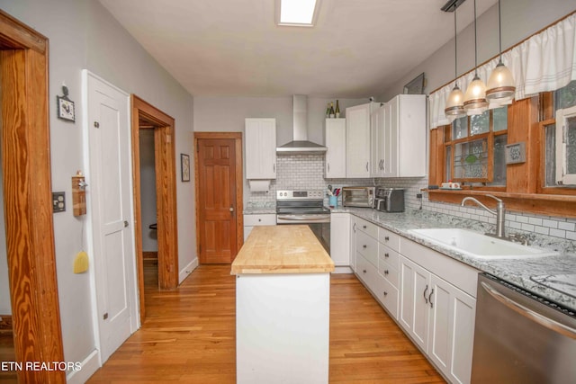 kitchen featuring wall chimney exhaust hood, a center island, white cabinetry, and stainless steel appliances