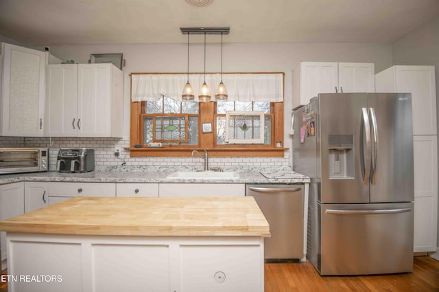 kitchen featuring decorative backsplash, appliances with stainless steel finishes, sink, light hardwood / wood-style floors, and white cabinetry