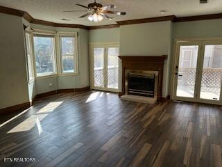 unfurnished living room featuring ceiling fan, dark hardwood / wood-style flooring, and ornamental molding