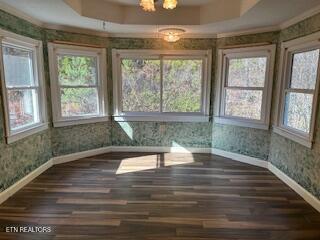 unfurnished sunroom with a tray ceiling and an inviting chandelier