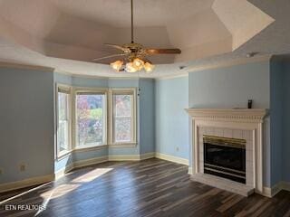 unfurnished living room featuring a raised ceiling, ceiling fan, and dark wood-type flooring