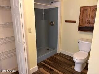 bathroom with hardwood / wood-style flooring, toilet, and walk in shower