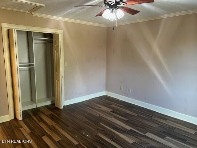 unfurnished bedroom featuring ceiling fan, dark hardwood / wood-style flooring, crown molding, and a closet