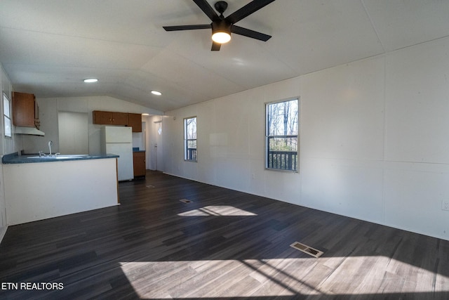 unfurnished living room featuring lofted ceiling, a wealth of natural light, ceiling fan, and dark hardwood / wood-style floors