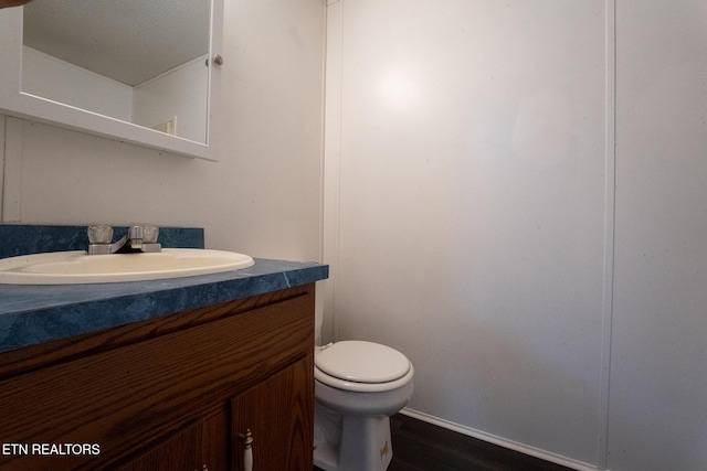 bathroom featuring wood-type flooring, vanity, and toilet