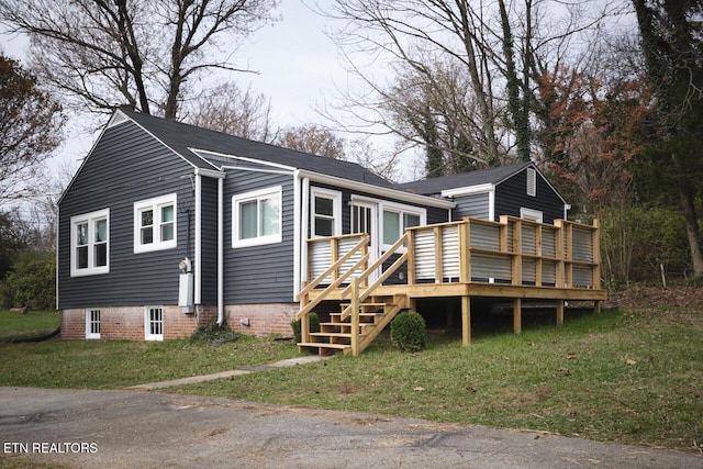 rear view of house featuring a lawn and a deck