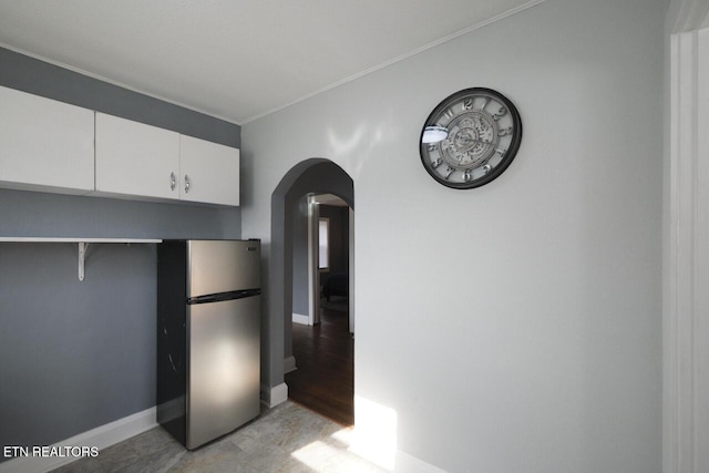 kitchen featuring stainless steel refrigerator, crown molding, white cabinets, and light wood-type flooring