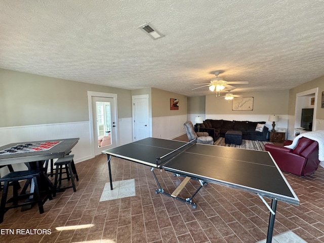 playroom with ceiling fan and a textured ceiling