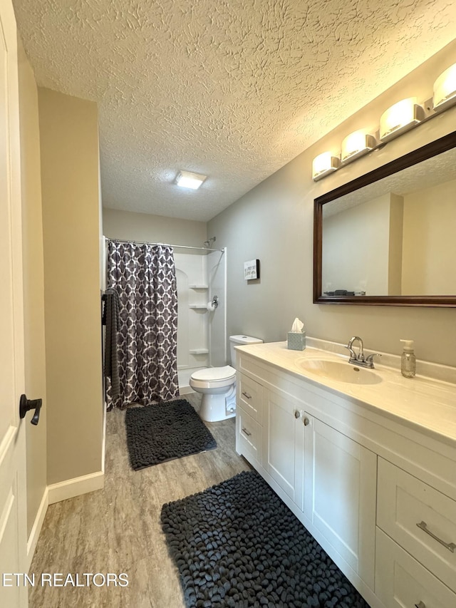 bathroom featuring walk in shower, vanity, toilet, hardwood / wood-style flooring, and a textured ceiling