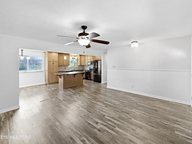 unfurnished living room with hardwood / wood-style flooring and ceiling fan