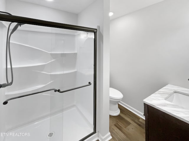 bathroom featuring wood-type flooring, vanity, toilet, and walk in shower