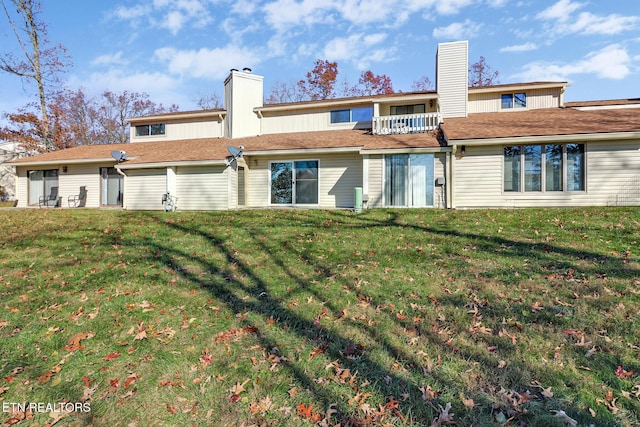 back of property with a lawn and a balcony