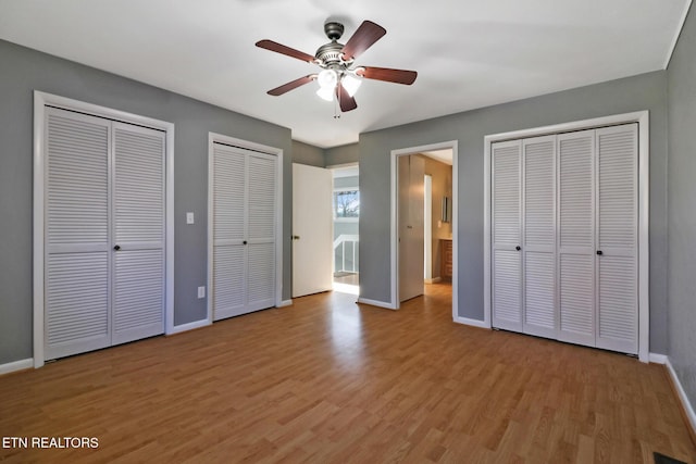 unfurnished bedroom featuring light wood-type flooring, ceiling fan, and multiple closets