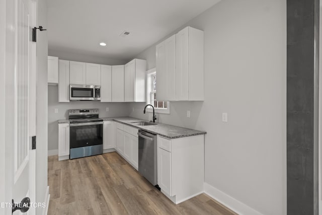 kitchen with white cabinets, stainless steel appliances, baseboards, and a sink