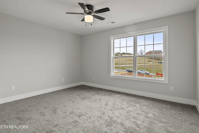 carpeted spare room with a ceiling fan, visible vents, and baseboards