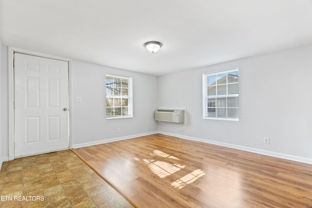 unfurnished room featuring a wall unit AC and hardwood / wood-style flooring