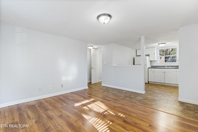 unfurnished living room featuring sink and light hardwood / wood-style flooring