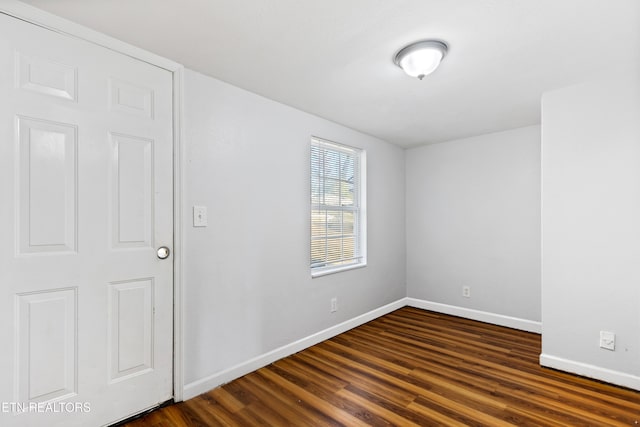 unfurnished room featuring dark wood-type flooring and baseboards