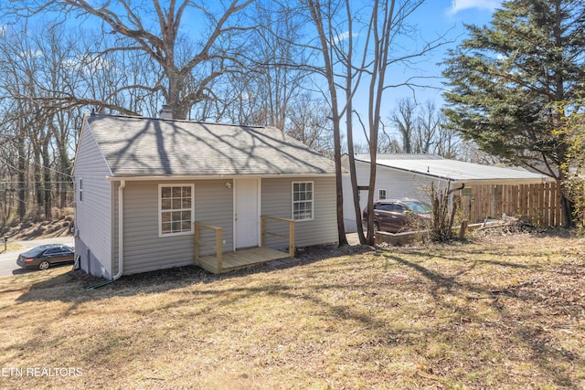 exterior space with a yard, a chimney, fence, and roof with shingles