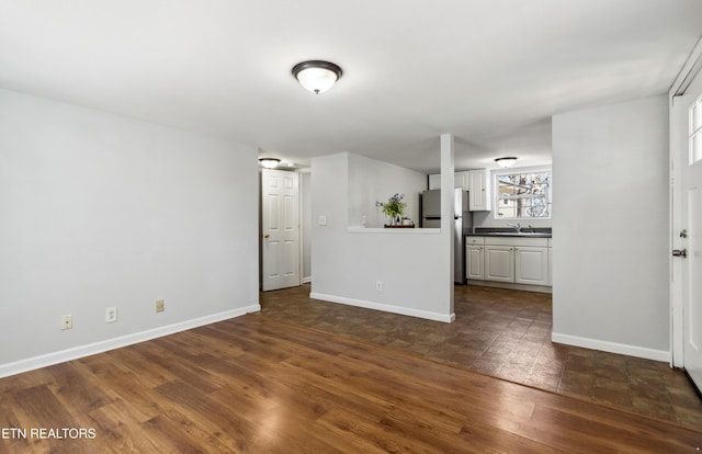 unfurnished living room featuring baseboards and dark wood finished floors