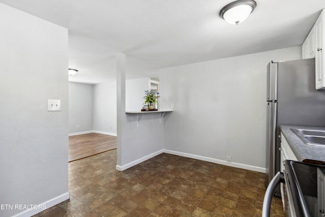 kitchen with baseboards, white cabinetry, and electric range oven