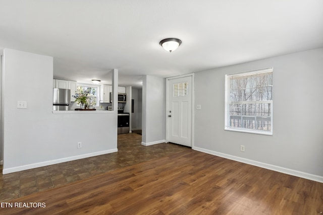 unfurnished living room featuring dark wood-style flooring and baseboards