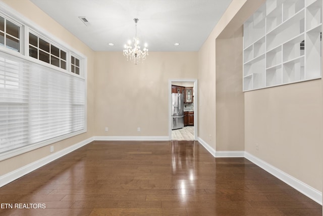 empty room with a chandelier and dark hardwood / wood-style floors